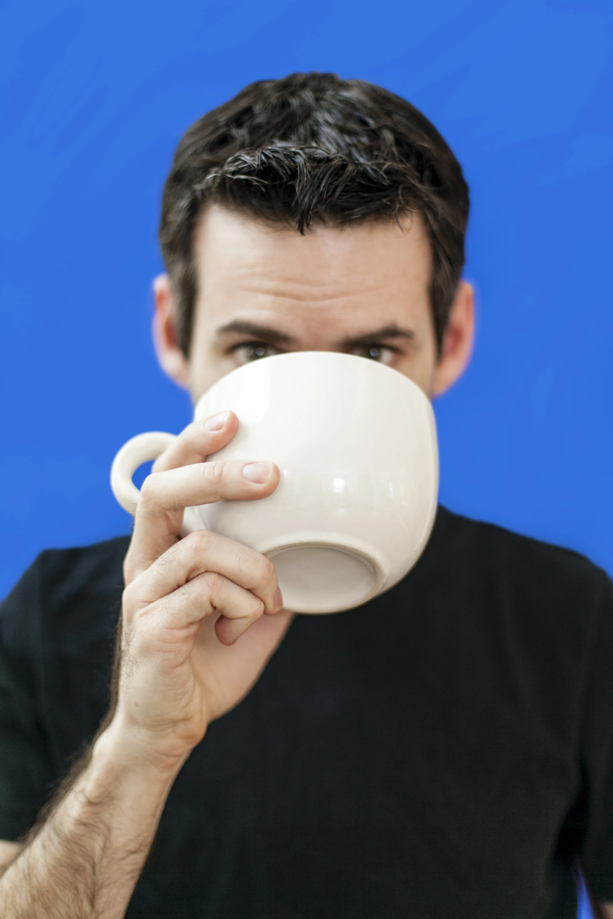 Jonathan Rand holding a white coffee mug against a blue background